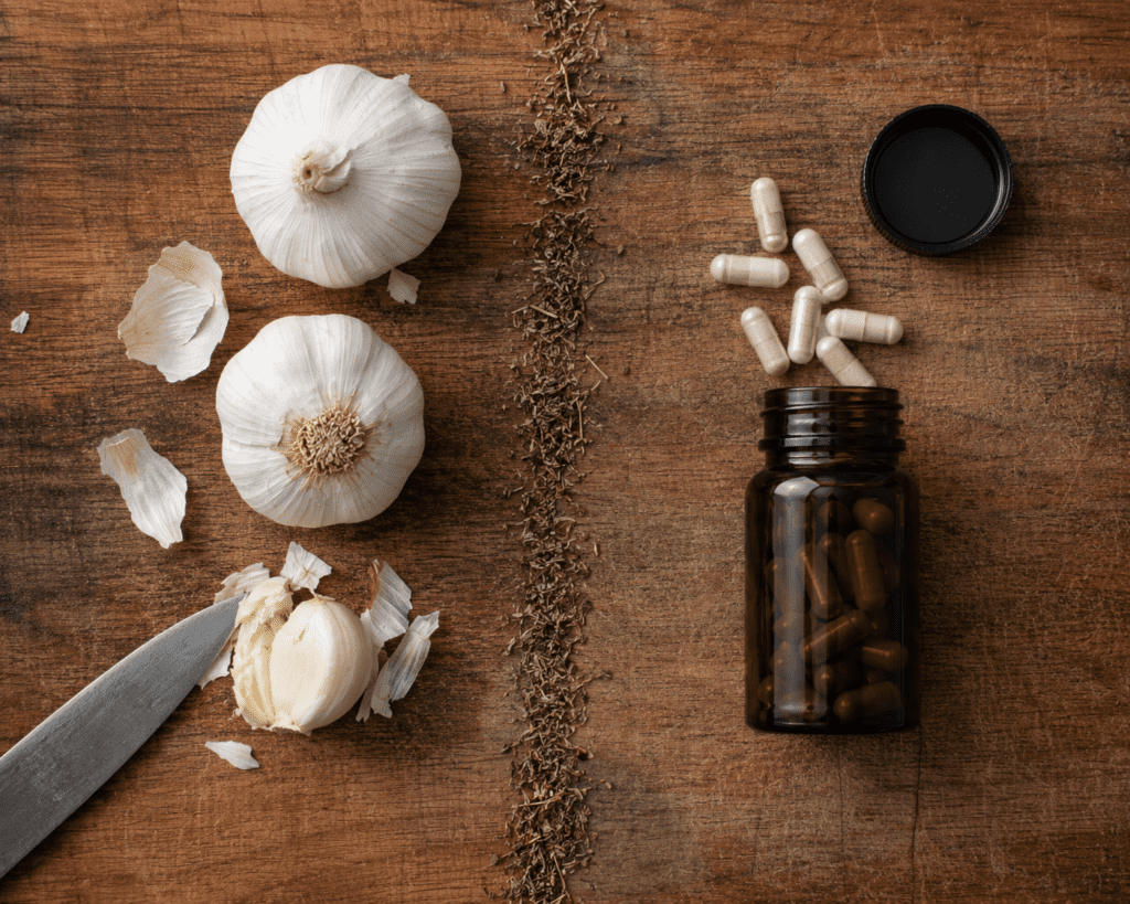 Raw garlic bulbs compared side by side with aged garlic extract supplement capsules
