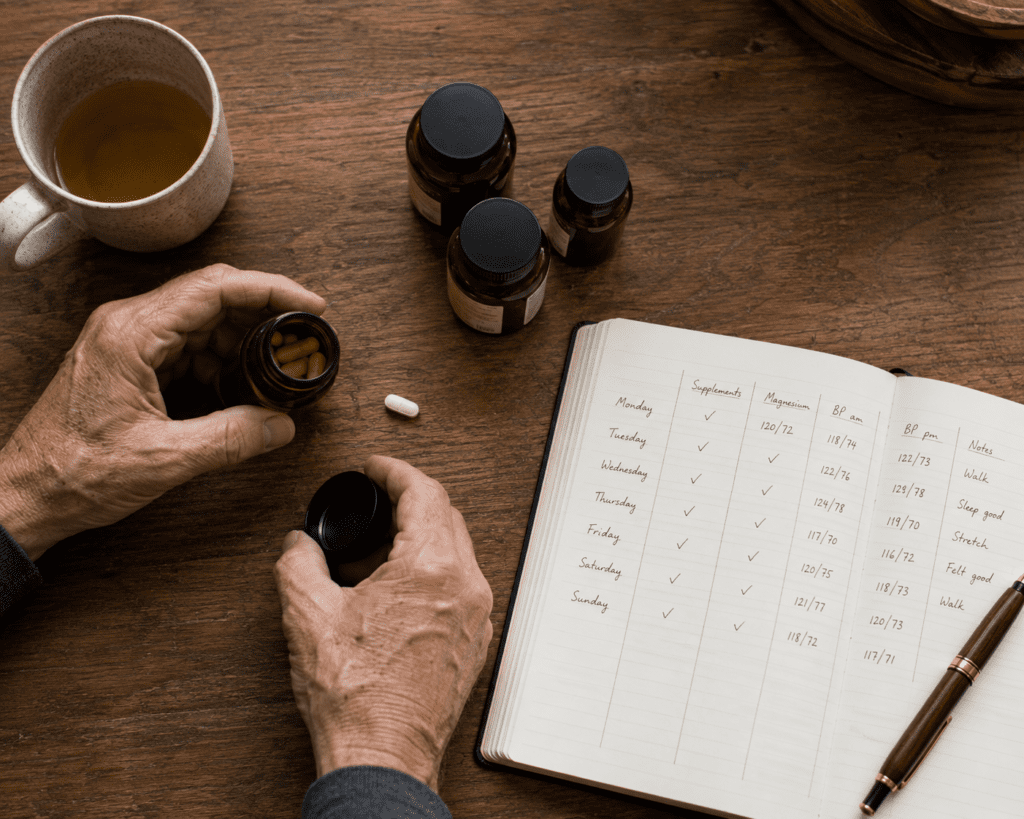 Older man's hands arranging natural fatigue supplements on kitchen table
